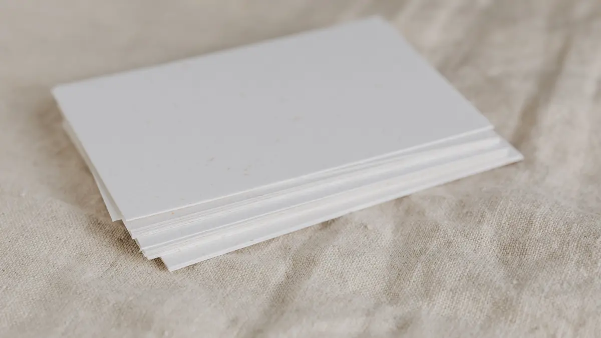 A small stack of blank paper on a linen surface