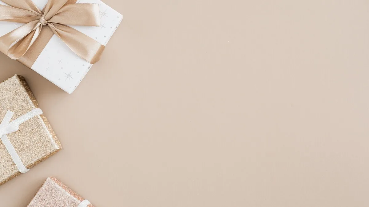 Gift boxes wrapped in kraft paper and ribbon on a warm beige surface
