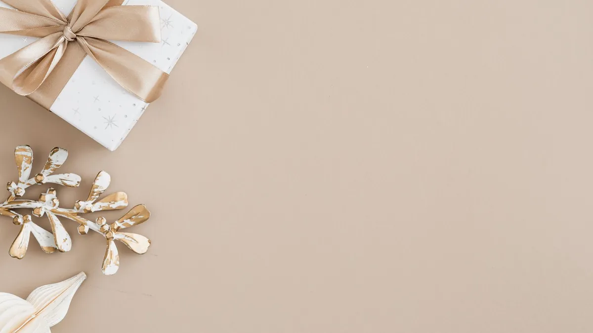 A wrapped gift box with a ribbon on a plain beige background