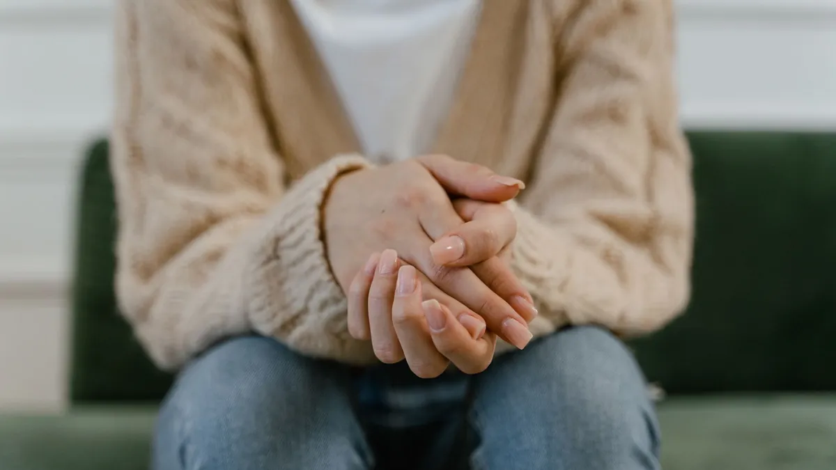 A person sitting with their hands resting quietly in their lap