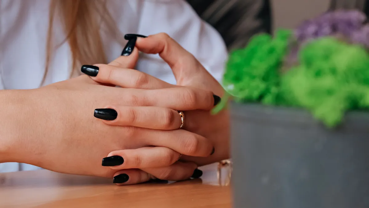 A pair of hands resting clasped on a wooden table