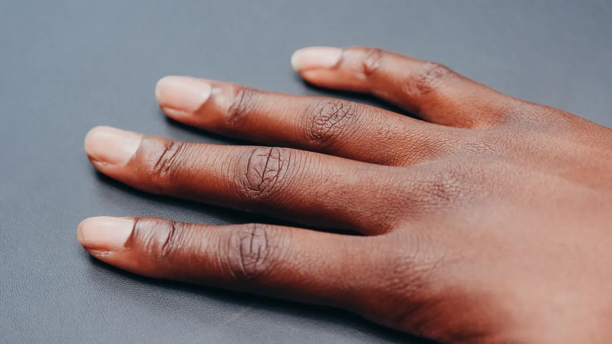 Close-up of a relaxed hand and fingers against a plain neutral background