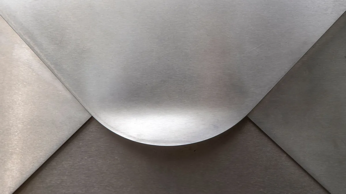 Close-up of a brushed silver metal surface with a soft curved fold